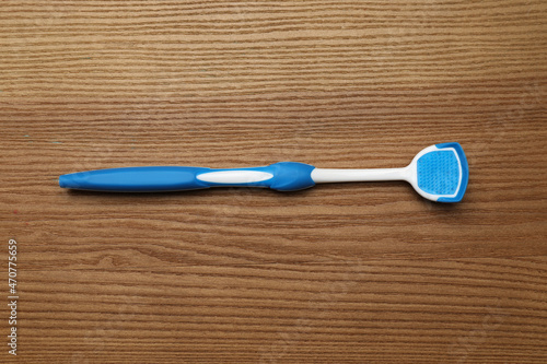 Blue tongue cleaner on wooden table, top view photo