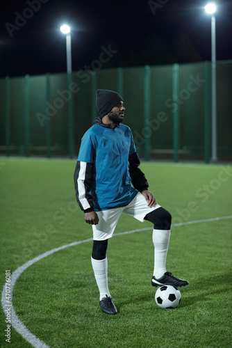 Young professional football player in uniform standing on green field with foot on soccer ball and waiting for start of game © pressmaster