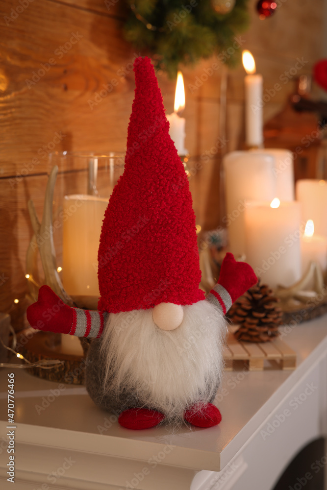 Obraz premium Cute Christmas gnome and festive decorations on mantelpiece in room