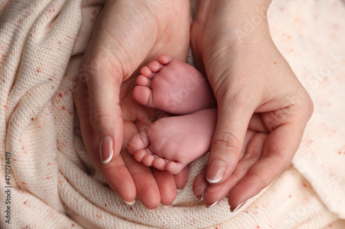 children's feet in mother's hands close-up. female palms. Heels of a newborn baby