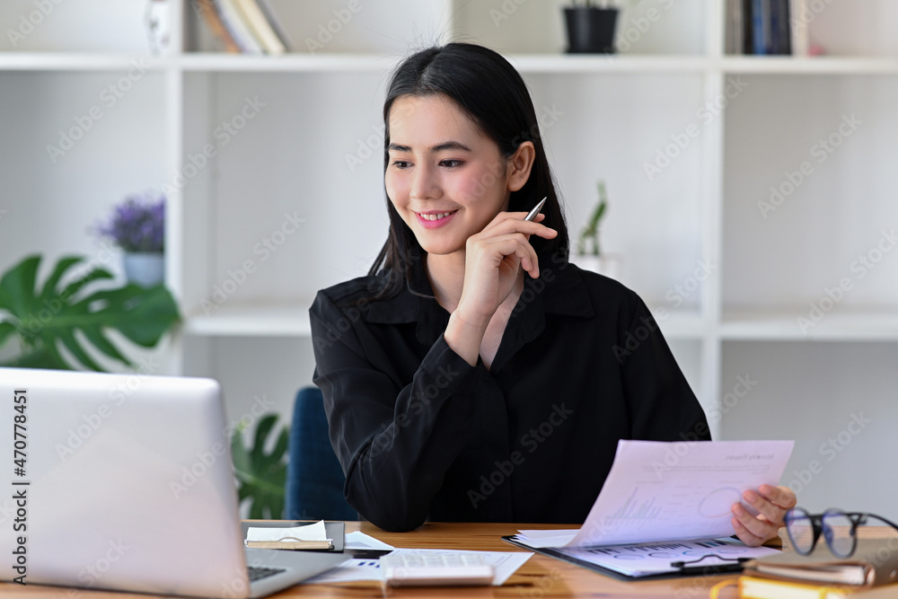Smiling businesswoman working with laptop and analyzing project statistics in office. Smiling businesswoman working with laptop and analyzing project statistics in office.