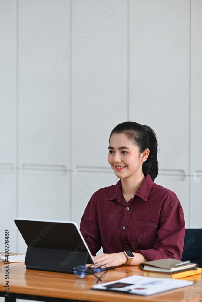Smiling businesswoman sitting at her office desk and working with computer tablet. Smiling businesswoman sitting at her office desk and working with computer tablet.