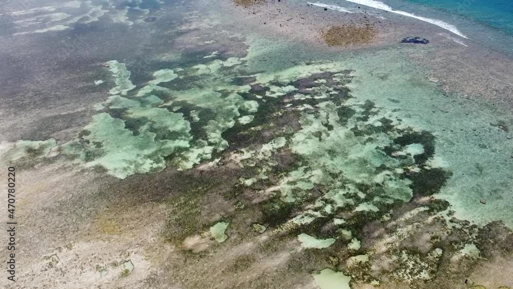 Aerial drone rising over crystal clear water at low tide on a remote, idyllic tropical island destination. Top down Birds eye view. Aerial drone rising over crystal clear water at low tide on a remote, idyllic tropical island destination. Top down Birds eye view.