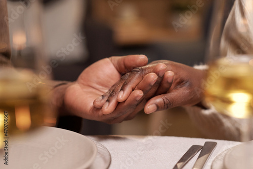 Hands of young African man and woman over served festive table during pray before Christmas dinner