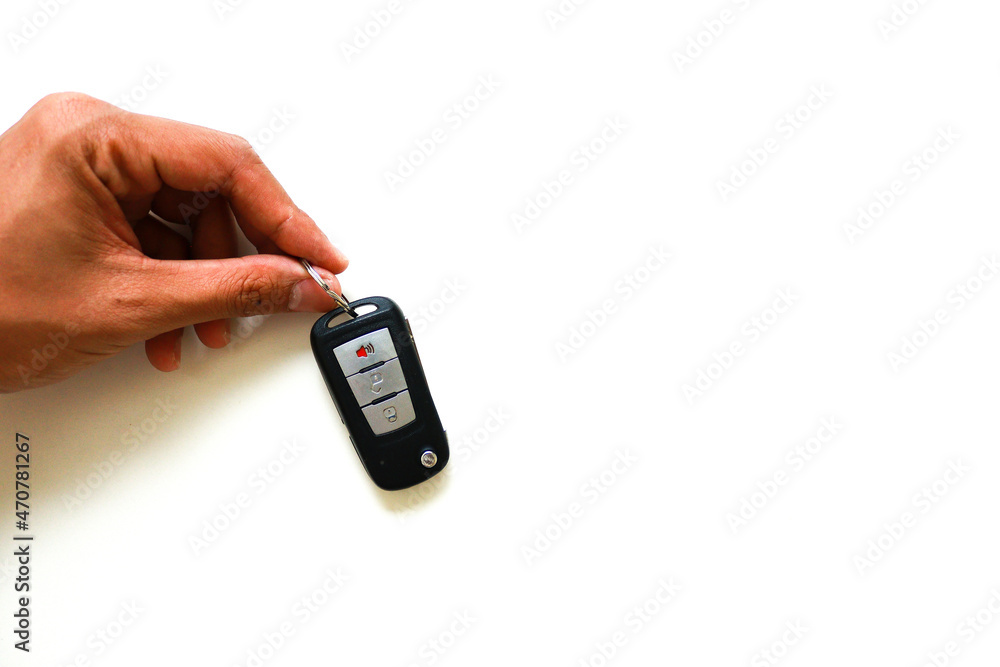 Hand holding a car key over isolated white background.