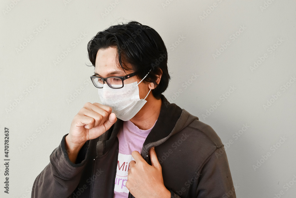 Asian male wearing a face mask over isolated background. Asian male wearing a face mask over isolated background.