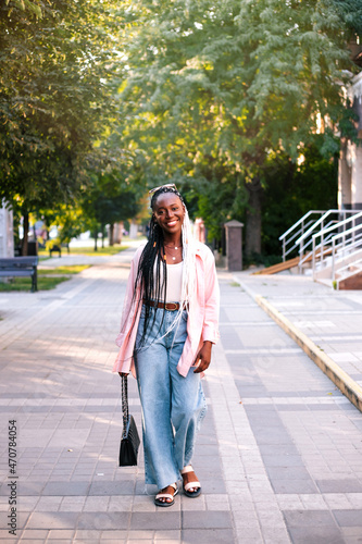 Beautiful black woman walking at street at summer. © Evgeniia