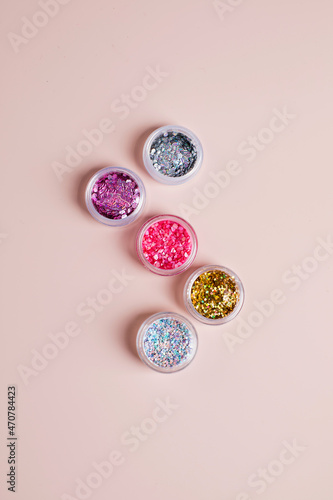 Shiny glitter powder for festive manicure Christmas party on pink background