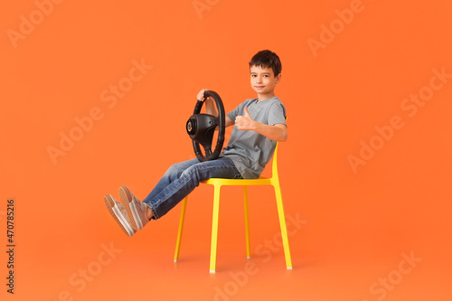 Little boy with steering wheel showing thumb-up on color background © Pixel-Shot