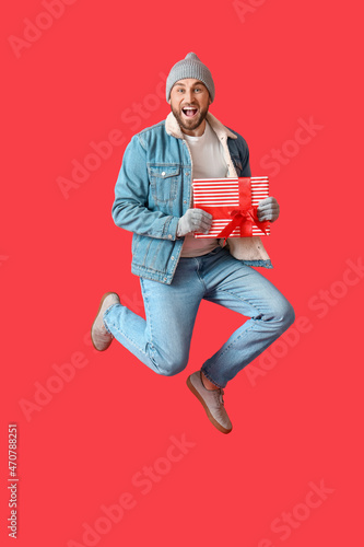 Jumping man with Christmas gift on color background