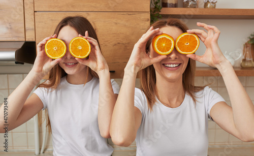 Foto Playful woman and girl with halved oranges