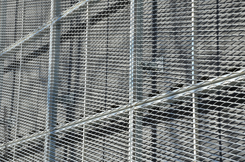 steel cladding of a building with a expanded metal lattice structure. galvanized gray nets protect the industrial building. Blue sky in contrast to a silver background