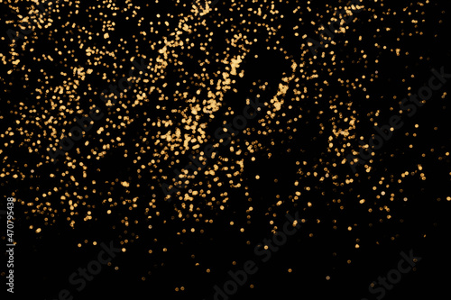 Black festive background. Abstract scattering of gold sparkles on black. Christmas backdrop, selective focus