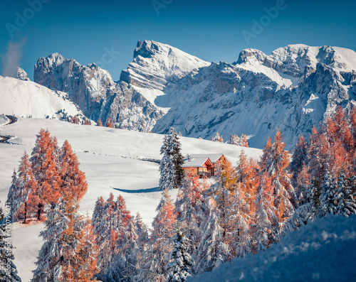 Two wooden chalets on mountain valley. Fabulous morning view of Alpe di Siusi village with Furchetta peak on background. Amazing winter scene of Dolomite Alps, Ityaly, Europe. photo