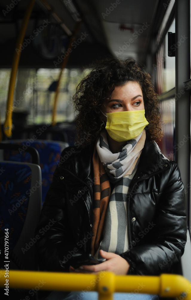 woman in a protective mask is riding the bus, observing the quarantine measures
