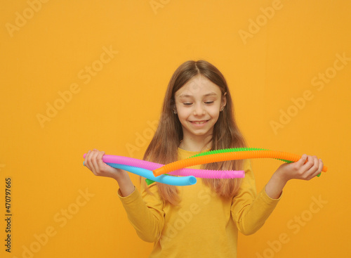 Playing little girl in yellow clothes with trendy toy pop tube.