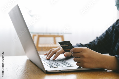 Fotografia Man Holding credit card and using a laptop with shopping online to buy a gift for girlfriend at the cafe