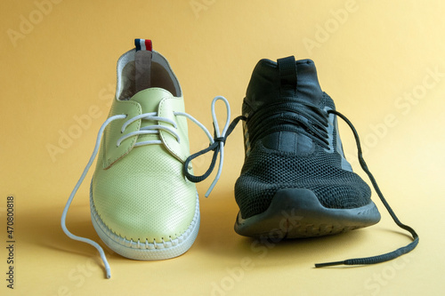 Male and female shoes linked on a yellow background. Concept-relationship between a man and a woman. Equality. Leather shoes. Men's trainer.