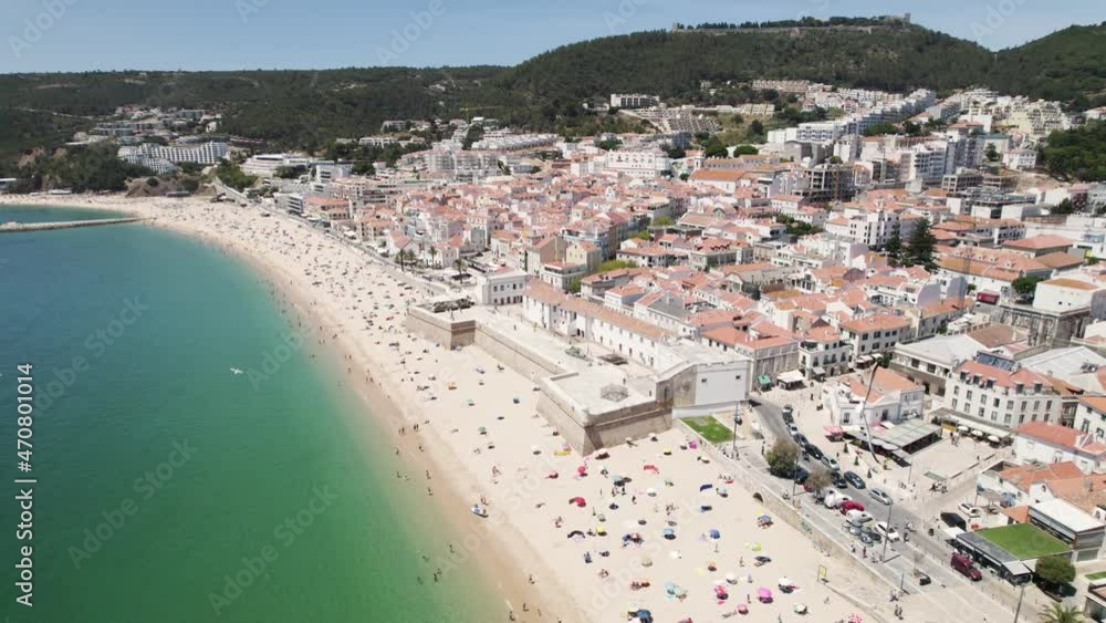 Sesimbra beach full of tourists during vacation, Aerial orbital drone shot Sesimbra beach full of tourists during vacation, Aerial orbital drone shot