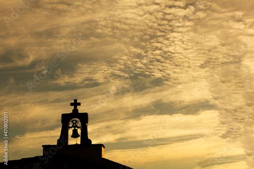 Φωτογραφία cross and bell tower of a hermitage backlit by a golden sunrise