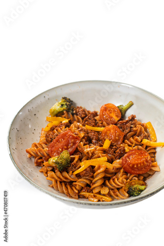 Vegan pasta with plant meat, tomato and olives on a white plate. Isolated on white.