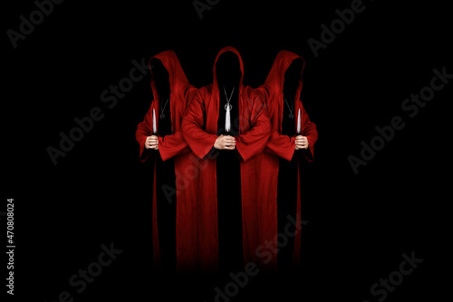 Mystery people in a red hooded cloaks in the dark holding ritual daggers. Hiding face in shadow.  Satanic symbols. Dark ritual. Sectarians. Isolated on black. photo