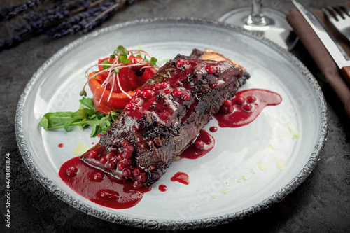 Baked beef rib with cranberry sauce. A dish of grilled beef on a bone and vegetables on a plate. photo