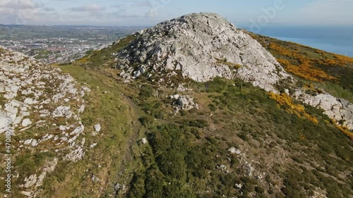 Drone video flying over Bray head one of Irish peaks with cross on top of it and sea and town in the background