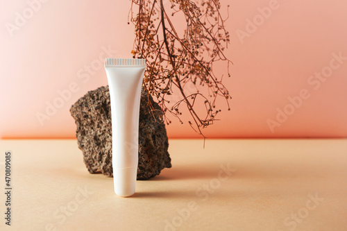 Fotografie, Obraz White plastic tube and stone and natural dry herb creative still life cosmetic photography