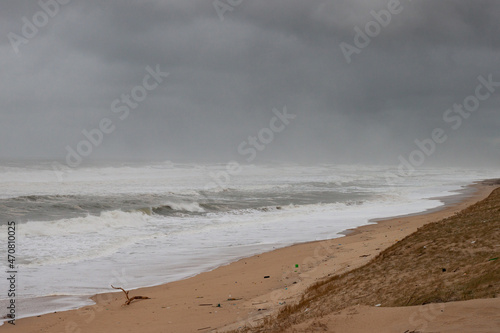 The beach on a stormy day. The waves break towards the beach, the ocean is raging, the sky is very dark and threatening. the beach has practically disappeared. photo