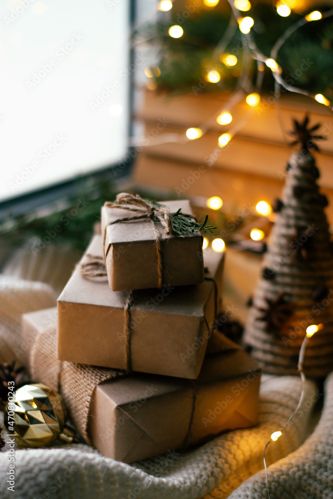 Gift boxes packed in craft paper and a homemade Christmas tree made of thread and cardboard on a festively decorated windowsill.New Year,Christmas and eco-friendly concept.Selective focus. Gift boxes packed in craft paper and a homemade Christmas tree made of thread and cardboard on a festively decorated windowsill.New Year,Christmas and eco-friendly concept.Selective focus.