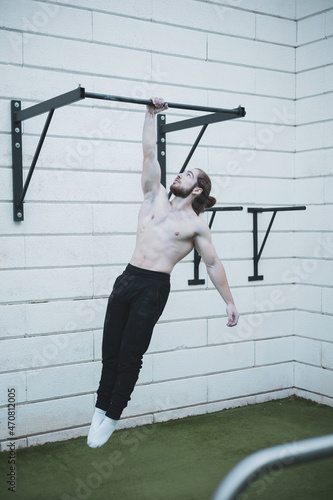 a red-haired boy with a ponytail doing calisthenics in a park.