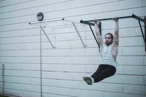 a red-haired boy with a ponytail doing calisthenics in a park.