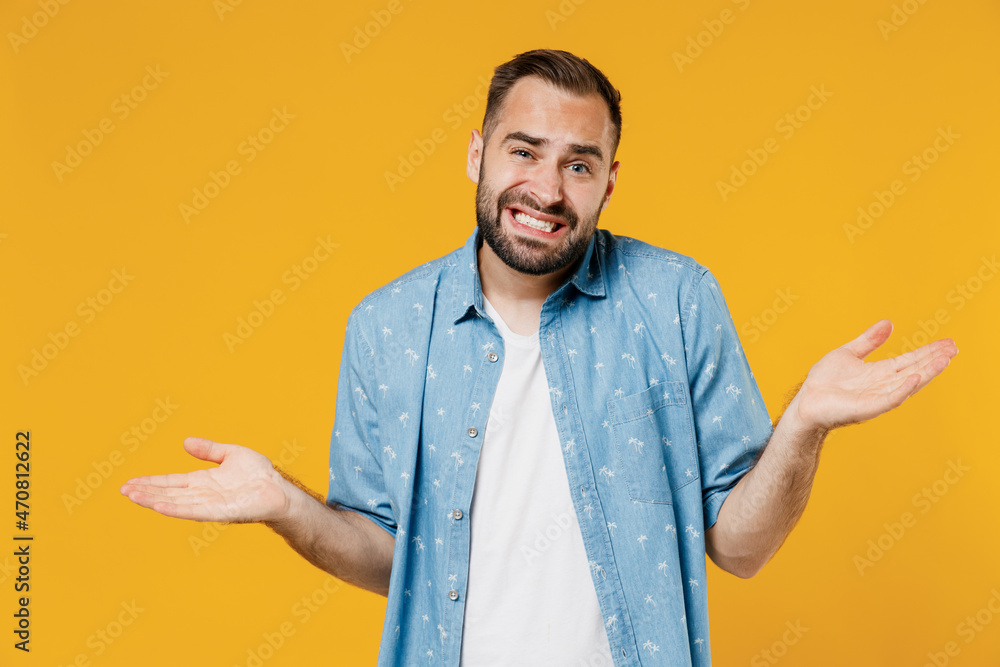 Young confused sad man 20s wearing blue shirt shrugging shoulders looking puzzled, have no idea, nothing to say, standing questioned and unaware isolated on plain yellow background studio portrait Young confused sad man 20s wearing blue shirt shrugging shoulders looking puzzled, have no idea, nothing to say, standing questioned and unaware isolated on plain yellow background studio portrait
