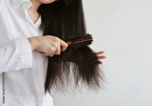 Asian woman combing her black hair with a round wooden brush photo