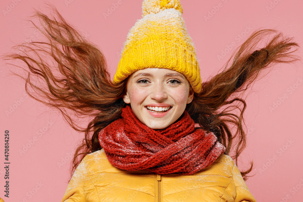 Happy jubilant excited fun young woman 20s years old wear yellow jacket hat mittens waving fooling around have fun enjoy fluttering hair isolated on plain pastel light pink background studio portrait Happy jubilant excited fun young woman 20s years old wear yellow jacket hat mittens waving fooling around have fun enjoy fluttering hair isolated on plain pastel light pink background studio portrait