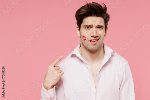 Fotografering Young sad caucasian man 20s with wearing casual shirt look camera point finger on lipstick lips on face cheek isolated on pink background studio