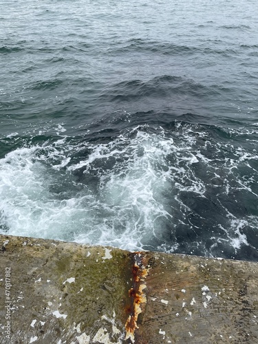 Vertical shot of waves washing over concrete pier at the sea