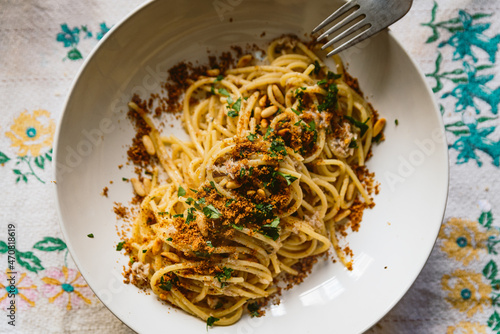 фотографія homemade italian pasta dish known as pasta con le sarde on table cloth, made with spaghetti, sardines, parsley, pine nuts and breadcrumbs