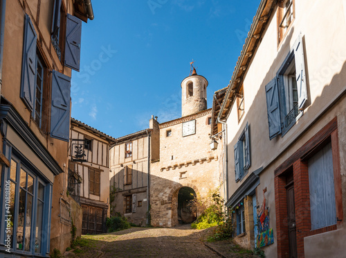 Old street and clock door  in the medieval village of Cordes sur Ciel in autumn  in the Tarn  Occitanie  France