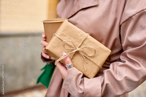 woman hold paper cup of coffee and carry gift box to congratulate friends or parents