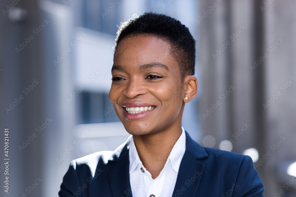 Headshot photo with close up portrait of young successful business woman, african american woman smiling and rejoicing looking at camera, in business suit, outside office Headshot photo with close up portrait of young successful business woman, african american woman smiling and rejoicing looking at camera, in business suit, outside office