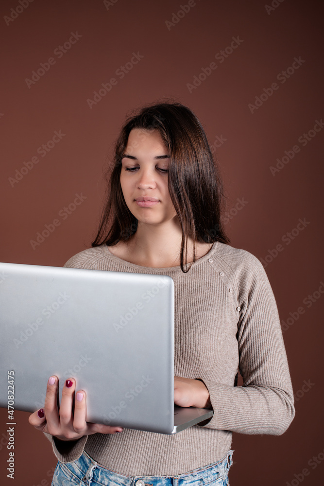 Beautiful woman with a laptop in her hands on a brown background. Business lady works online. Beautiful woman with a laptop in her hands on a brown background. Business lady works online.