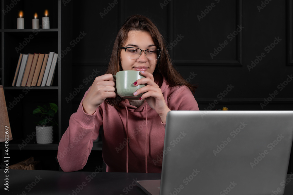 Pretty woman is typing on the laptop keyboard while sitting in the office. A student is preparing for an online conference. Pretty woman is typing on the laptop keyboard while sitting in the office. A student is preparing for an online conference.