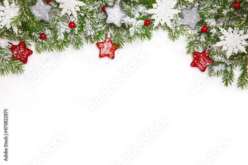 Christmas border with fir branches, decorations, berries and snowflakes. New year border isolated on white, composed of fresh fir branches and ornaments in red and silver