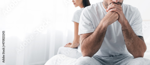 Cropped depressed millennial european male sits on bed, ignores offended sad female in bedroom interior