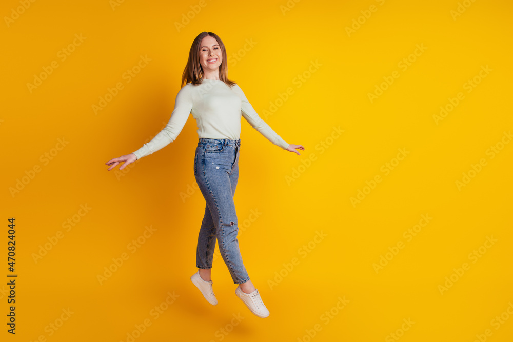 Photo of carefree girlish lady jump go wear green shirt jeans footwear isolated on yellow background Photo of carefree girlish lady jump go wear green shirt jeans footwear isolated on yellow background
