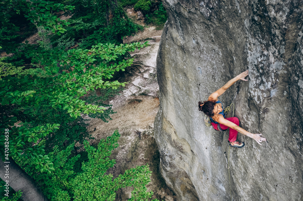 Obraz premium Beautiful Woman Climbing on the High Rock in the Mountains. Adventure and Extreme Sport Concept