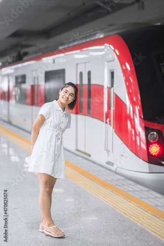 Happy woman waiting train at public transportation station. Tourist and Travel concept photo