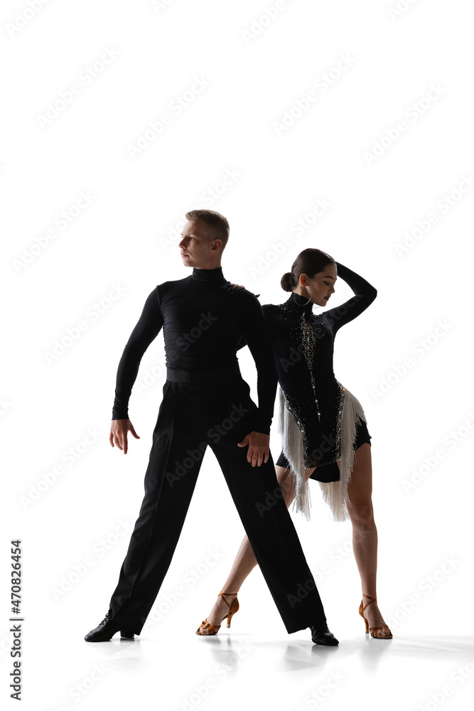 Two young graceful dancers, flexible man and woman dancing ballroom dance isolated on white studio background. Two young graceful dancers, flexible man and woman dancing ballroom dance isolated on white studio background.